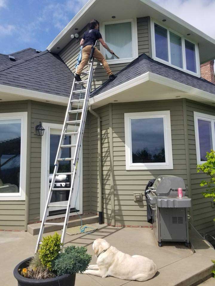photo of an Envision Property Maintenance employee climbing a ladder to wash windows
